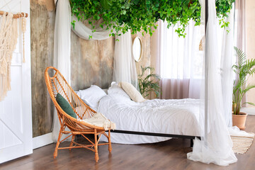 Interior boho design bedroom with garland flowers and plants. Cozy light bedroom in Scandinavian...