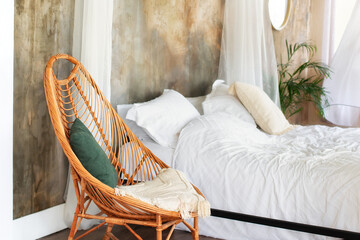 Design wicker wooden chair with pillows in stylish light bedroom interior. Modern Rattan armchair...