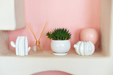 Stylish interior of Scandinavian style living room with design shelf with home decoration, aroma diffuser, cactus figurines and plants in pots. Template. Modern home decor. Collection of cacti in pots