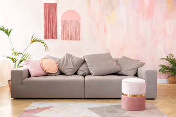 Modern room interior with comfortable sofa and and pink pouf for seating. Cozy living room interior...