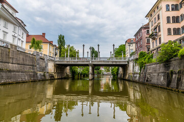 Fototapeta premium A view along the Ljubljanica River towards the Shoemakers Bridge in the center of Ljubljana, Slovenia in summertime