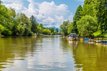 Obraz premium A view past moored boats on the Ljubljanica River on the outskirts of Ljubljana, Slovenia in summertime