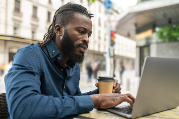 Obraz premium Dark-skinned young man working in a cafe outdoors