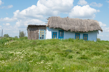 Traditional Danube Delta house. House with a thatched roof. White and blue seaside house. Danube Delta holyday.
