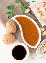 Top view of a sauce dish with ingredients: parsley, almonds, walnuts, soy sauce, walnuts and pine nuts