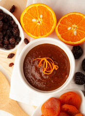 Top view of a plate of sauce with ingredients: orange, raisins, dried apricots, prunes,