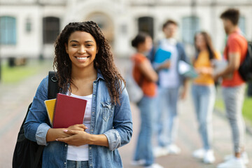 Loans for education concept. Portrait of happy black female student posing outdoors