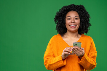 Curly-haired young woman in orange with a smartphone in hands