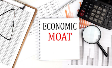 ECONOMIC MOAT text on notebook with clipboard and calculator on a chart background