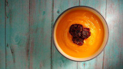 pumpkin cream soup on a blue wooden table . lunch is vegan. restaurant menu . copy space