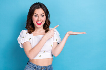 Photo of pretty excited lady wear white blouse showing finger holding arm empty space isolated blue color background