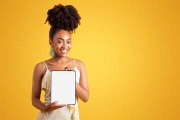 Cheerful young black woman showing tablet with empty screen, recommending social media app