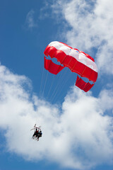 Red parachute in the blue sky with people ina cloudy day