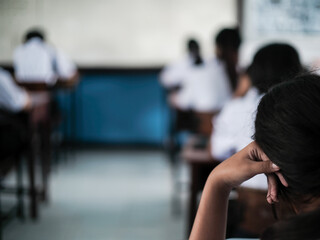 Students reading exam answer sheets exercises in classroom of school with headache.and stress