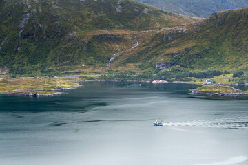 Motorboat sailing on calm fjord surrounded by mountains