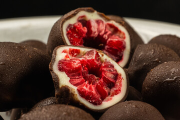 close-up of raspberry dipped in two layers of black and white chocolate, ideal for potre or snack