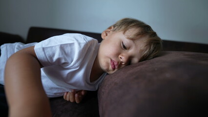 Obraz na płótnie Canvas Child lying down on sofa resting kid lies down on couch napping