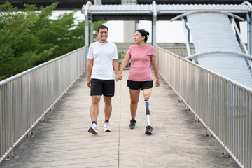 Exercise Asia woman with prosthetic leg holding hand boy friend in the park city	