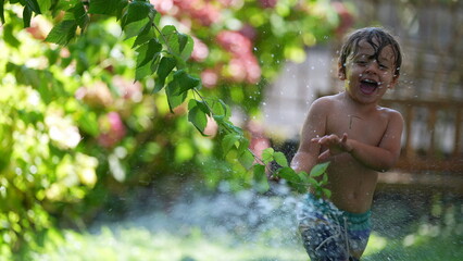 Child playing outside with water spray laughing and smiling