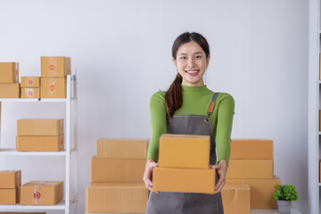 Startup happy Asian woman business owner works with a box at home, prepare parcel delivery SME supply chain, procurement, package box to deliver to customers, Online SME business entrepreneurs ideas,
