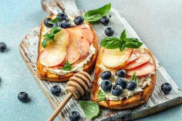 Bruschetta with peach, ricotta, blueberries on a wooden board, Food recipe background. Close up