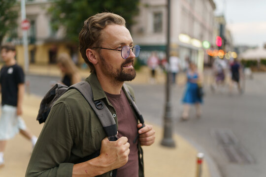 Traveler standing on pedestrian crossing in picturesque streets of old city. Man, adorned with backpack, exudes sense of adventure and wanderlust as he immerses himself in charm of old Europe. . High