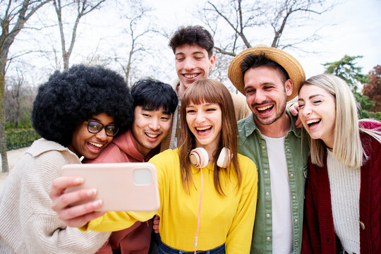 Group of multiracial students and laughing a lot while they they look at a phone. They look happy and friendly while the check multimedia in a device.