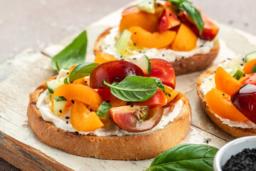 Gourmet sandwiches bread toast, bruschetta with cream cheese, peaches, tomatoes and green basil leaves - obrazy, fototapety, plakaty