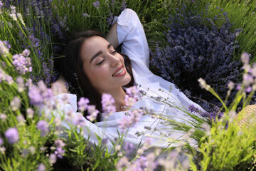 Young woman lying in lavender field on summer day