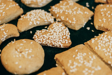 Homemade cookies with sesame seeds of different shapes with a heart-shaped cookie in the center.