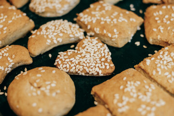 Homemade cookies with sesame seeds of different shapes with a heart-shaped cookie in the center.
