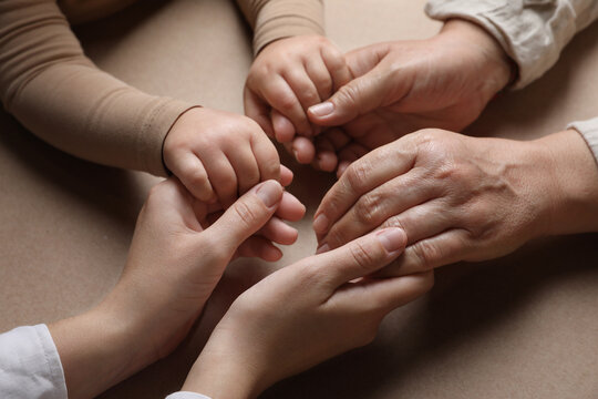 Family holding hands together on brown background, closeup