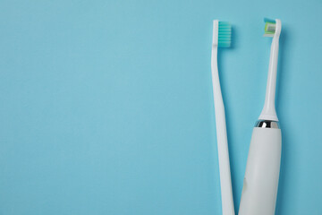 Electric and plastic toothbrushes on turquoise background, flat lay. Space for text