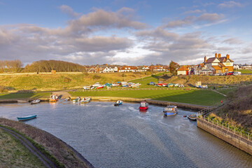 The early morning sun lights up the village of Seaton Sluice across the Seaton Burn, in Northumberland.