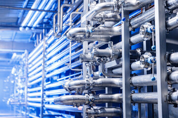 Pipes stainless steel brewing equipment, large reservoirs or tanks in modern beer factory. Brewery production concept, industrial blue background
