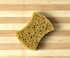 Sponge for washing dishes lies on a striped wooden cutting board