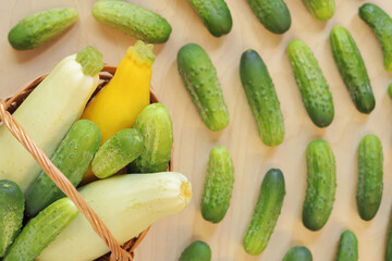 Zucchini and cucumbers in a basket, top view. Harvest of vegetables on a wooden background