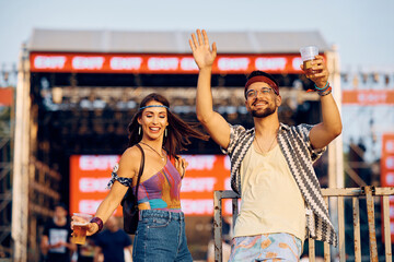Happy couple dancing and having fun on concert during music festival.