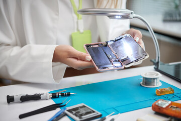 Closeup image of technician examination broken smartphone before repairing