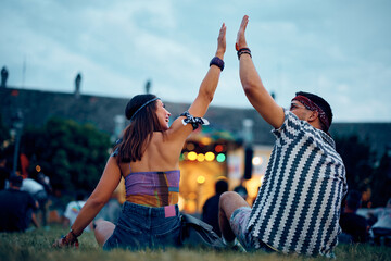 Happy couple giving high five at summer music festival.