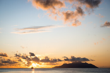 Silhouette of a sailing ship on the background of a fiery sunset. Beautiful sunset on Mahe island in Seychelles.