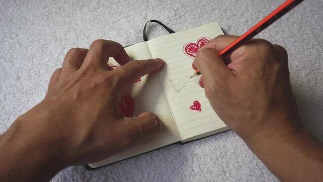 Latin man hands. Hands writing the word love on an agenda. Hearts and writing. hands in action