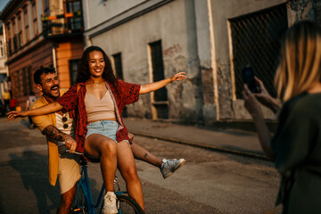 Two couple tourists enthusiastically ride on bicycle, having fun while exploring the city