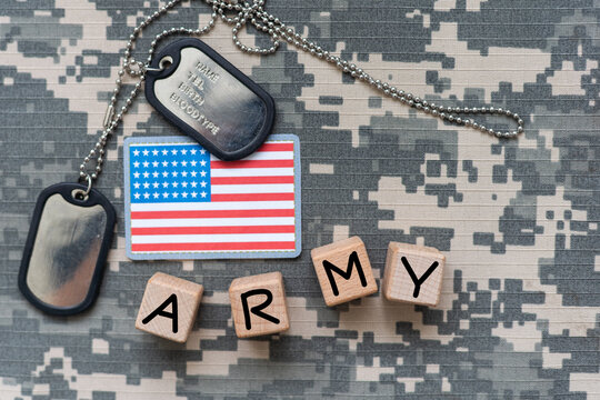 Military ID tags and US army patches on camouflage background, flat lay