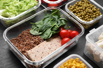 Glass and plastic containers with fresh food on black table, closeup