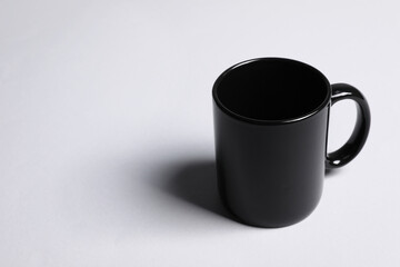 One black ceramic mug on light grey background, space for text