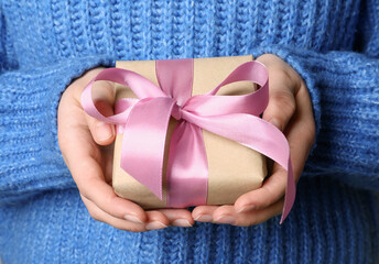 Woman holding gift box with pink bow, closeup