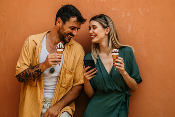 A young tourist couple laughs as they share a large ice cream sundae, making the most of their day...