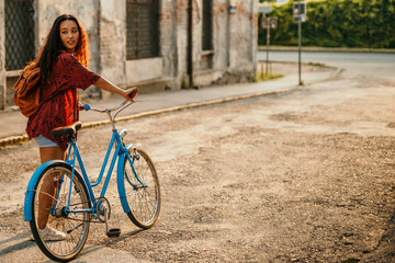 Fototapeta na wymiar Cheerful Asian woman pushing her bicycle in the old town of the city during sunset.