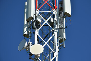Telecommunication tower with white antenna. Blue sky in background